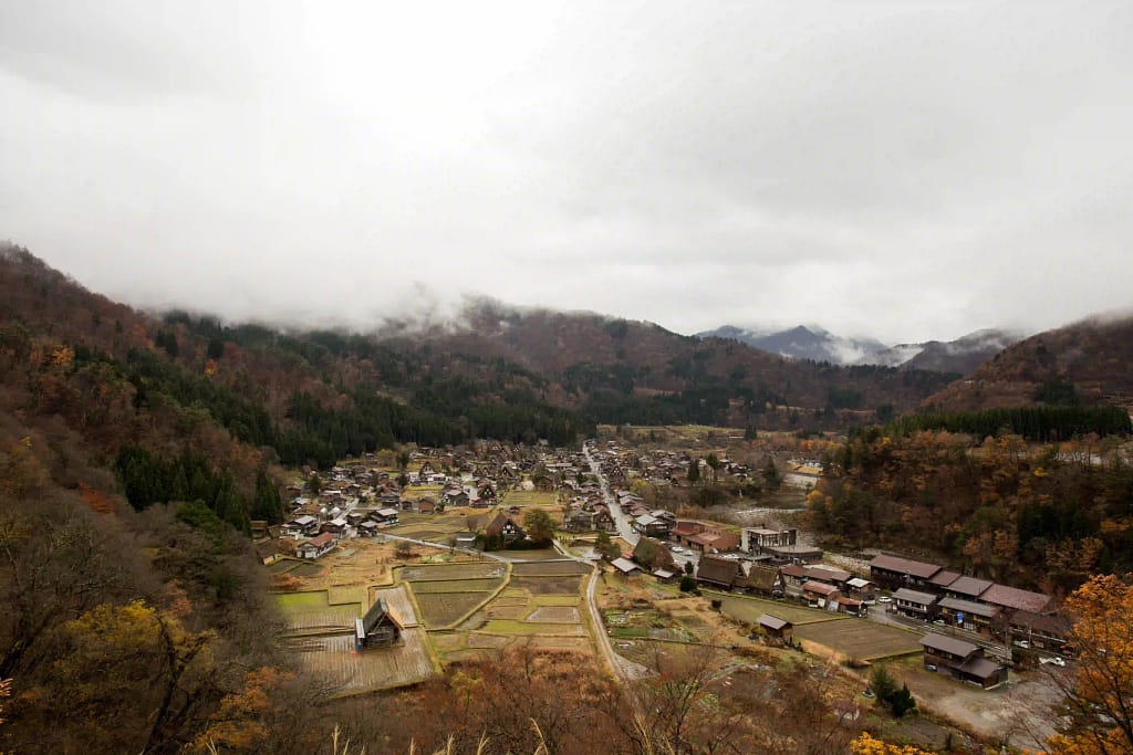 An aerial view of a small and cozy town surrounded with nature, trees and hills. 