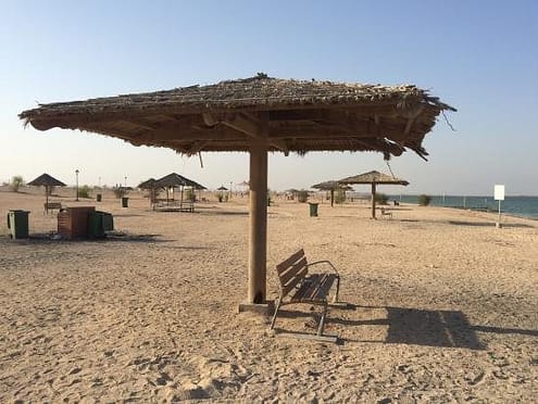a shade with a wooden chair in a beach in must-visit tourist sites in Al Khor, Qatar