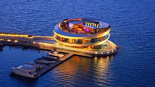 a building with lights in the middle of a blue ocean in top 10 restaurants in Qatar