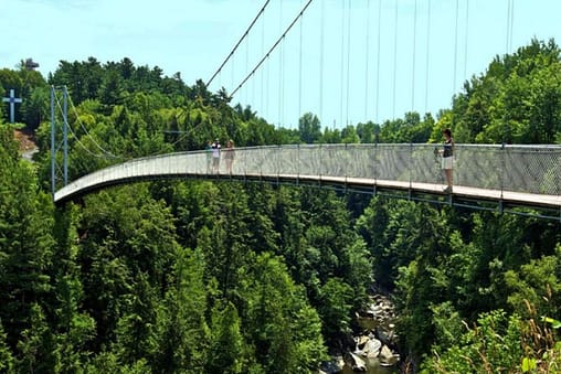 people walking on a bridge across a forest in top sites to visit in Granby, Canada