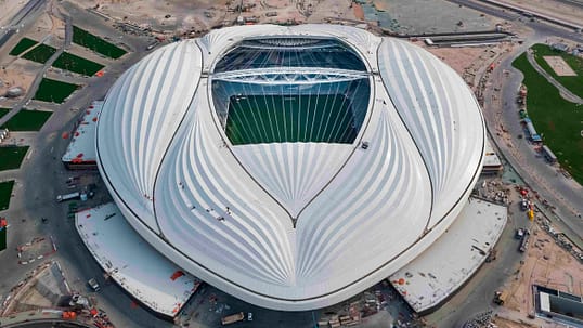 people walking by a large white stadium in tourist destinations in Al Wakrah, Qatar.