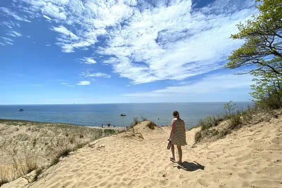 A lady walking on the Saugatuck Dunes State Park opposite the sea shore