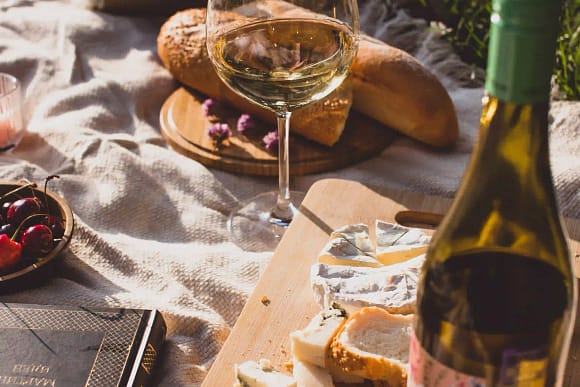 A glass of wine, bread and cheese. 