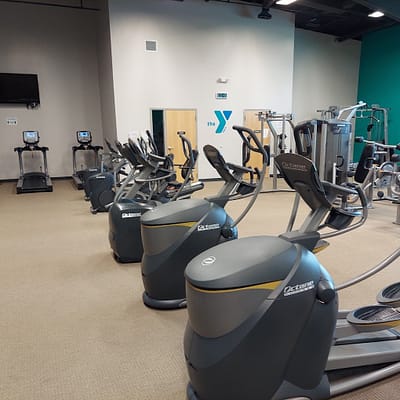 A group of fitness/gym equipments in a large hall inside the Cameron Regional YMCA