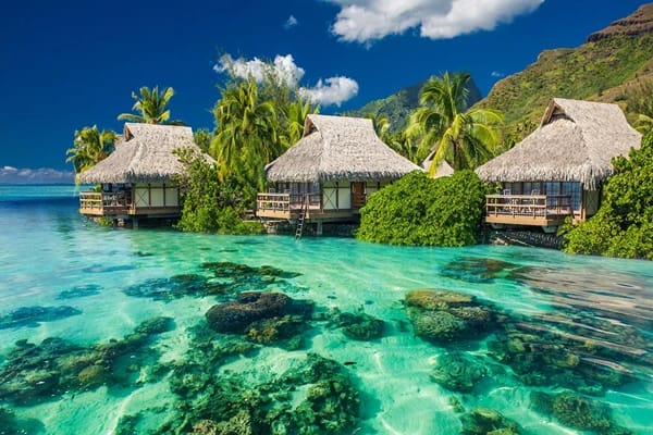 Beautiful clear waters surrounded but hut houses  and mountains 