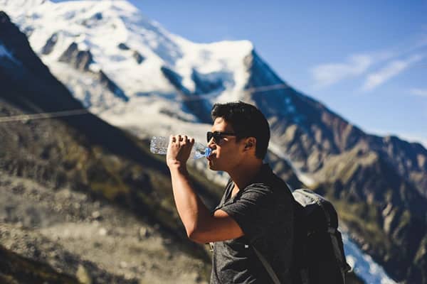 Man drinking a bottle of water while on the mountains