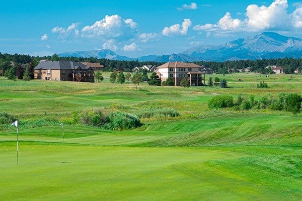 a golf course with buildings and the mountains in the background