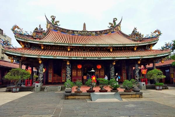 A beautiful red and blue coloured temple in Taiwan with tourists at the entrance