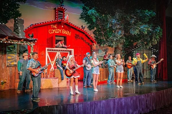 People on stage with guitars performing for an audience.