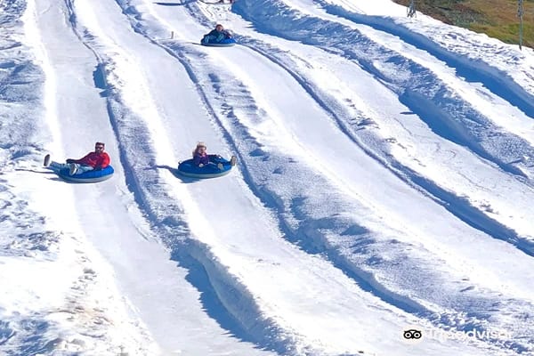 Three people sliding down a snow slide