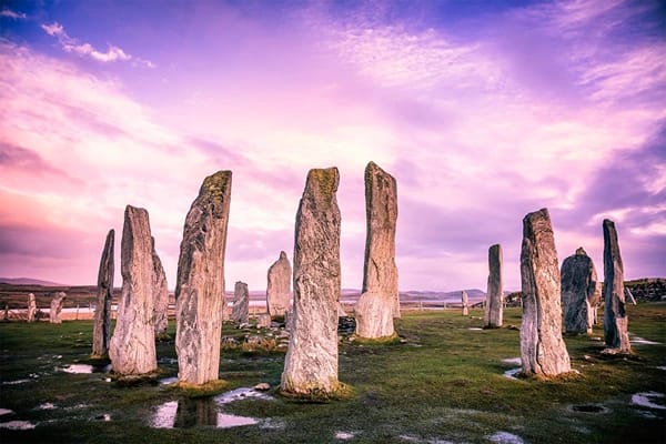 Stone monuments on a watery ground under a purple sky