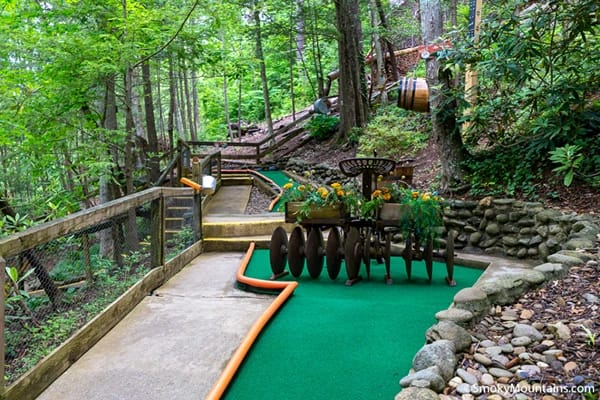 A mini-golf courses surrounded by a forest with stones, trees and plants.