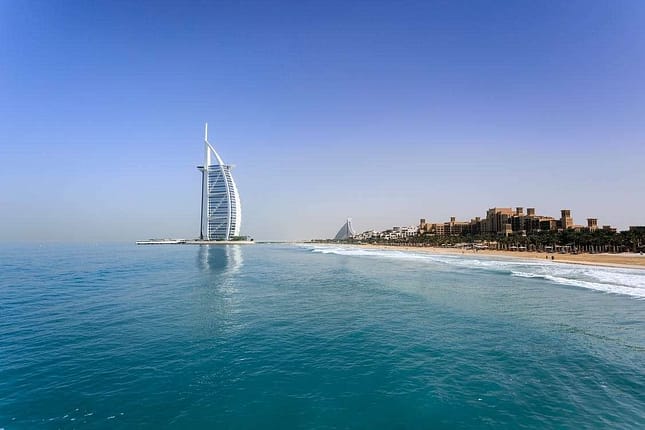 Burj Al Arab, Dubai, surrounded by a large body of water and tall sky scrapers