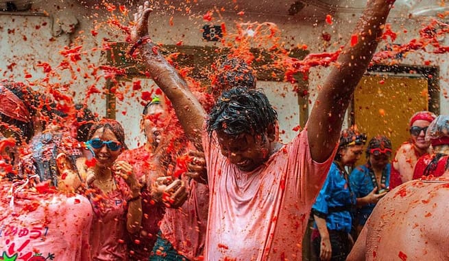 A group of people soaked and stained with red Tomatoes in a festival at La Tomatina, Valencia, Spain