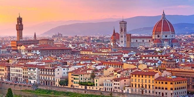 An aerial view of a city in Florence under a yellow sunset cloud