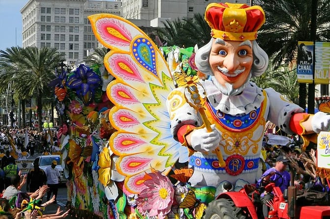 A huge masquerade being ridden on a truck in the street with people celebrating 