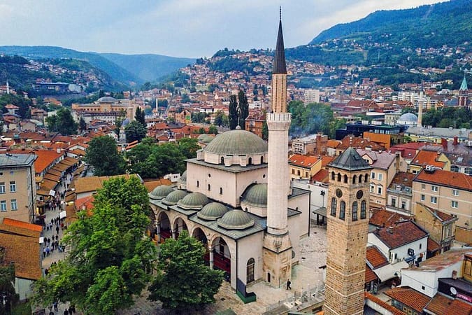 A large area in Sarajevo with lots of beautiful tall and short houses surrounded by high plains and mountains