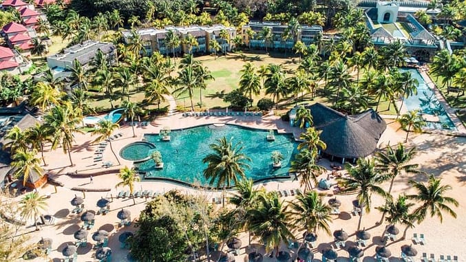 Aerial view of the Outrigger Beach Resort in Mauritius with tall palm trees, a swimming pool, and several apartments