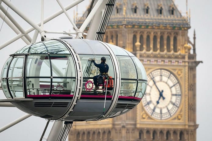 A cleaner cleaning one of the Pods of the London Eye.