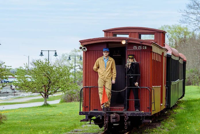 Two men standing in front of a stationary train in Gladwin City Park