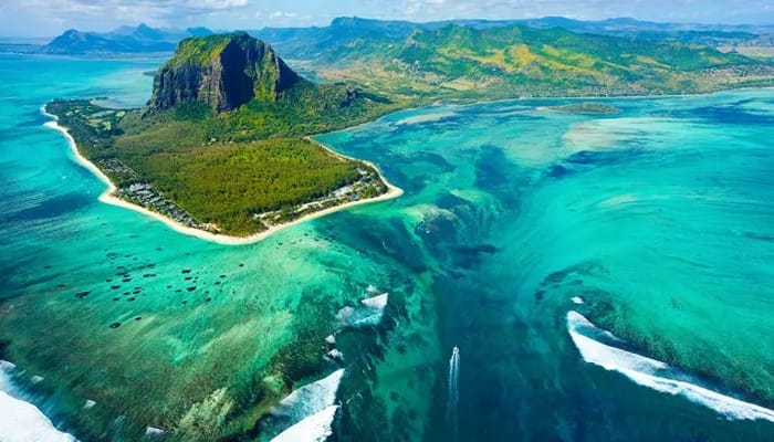 A very beautiful scene in Mauritius showing a large body of crystal clear waters bordering an island like bed of mountains.