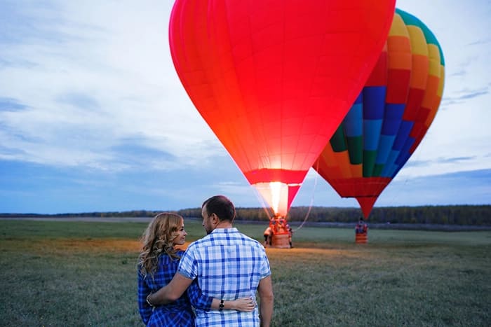 A couple holding hands in front of two hot air balloons