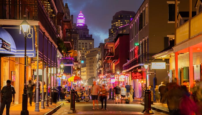 A well lit street in New Orleans, Louisiana in the night with people walking in different directions