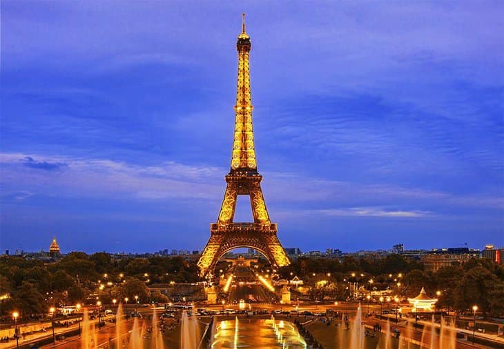 The Eiffel Tower, Paris, showing the tall tower glowing in gold colors in the evening