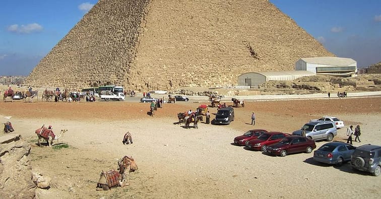 A Pyramid in Egypt with lots of tourists and cars packed around