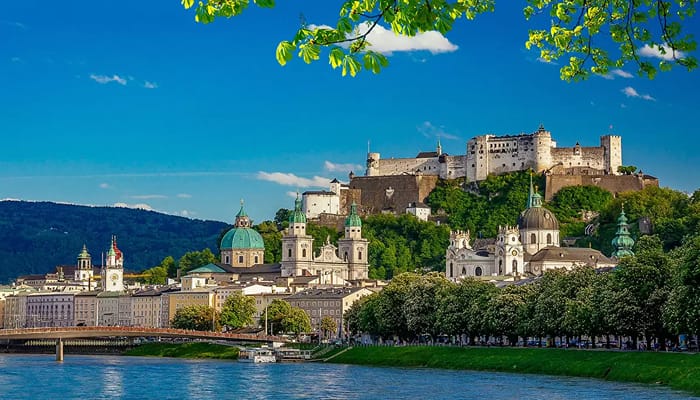 A beautiful image of Salzburg, Austria the city's musical heritage with houses and huge vegetations close to a beach.