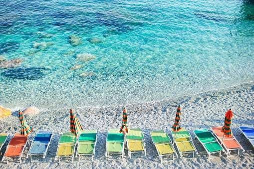 A beach in Monterosso Al Mare, Italy showing different coloured seats