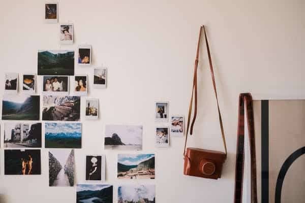 Different old photos placed on the wall with an old camera hanged on the wall.