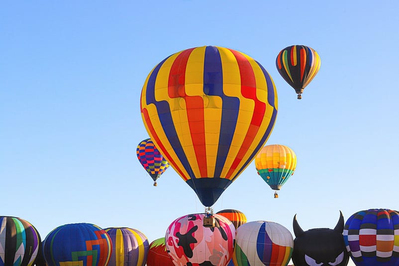 Different colourful hot air balloons flying in the open air.