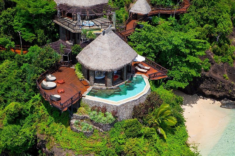 Hilltop Villa - Laucala Island, Fiji - $50,000A hut and swimming pool close to a beach, surrounded by green trees 