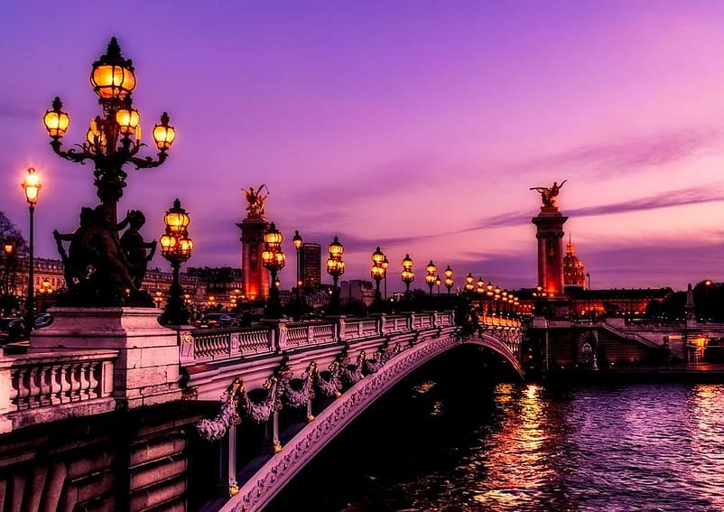 A lovely pink cloud of sunset over a bridge with a lot of lights in Paris, France