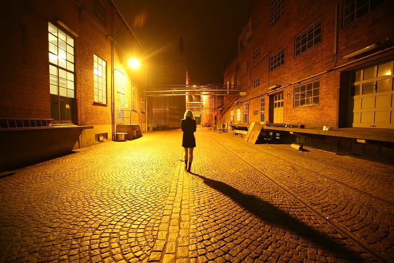 A lady walking alone in a quiet neighbourhood at night.